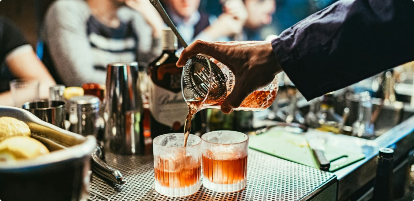 Man pouring a refreshing cocktail into a glass with ice cubes and garnish