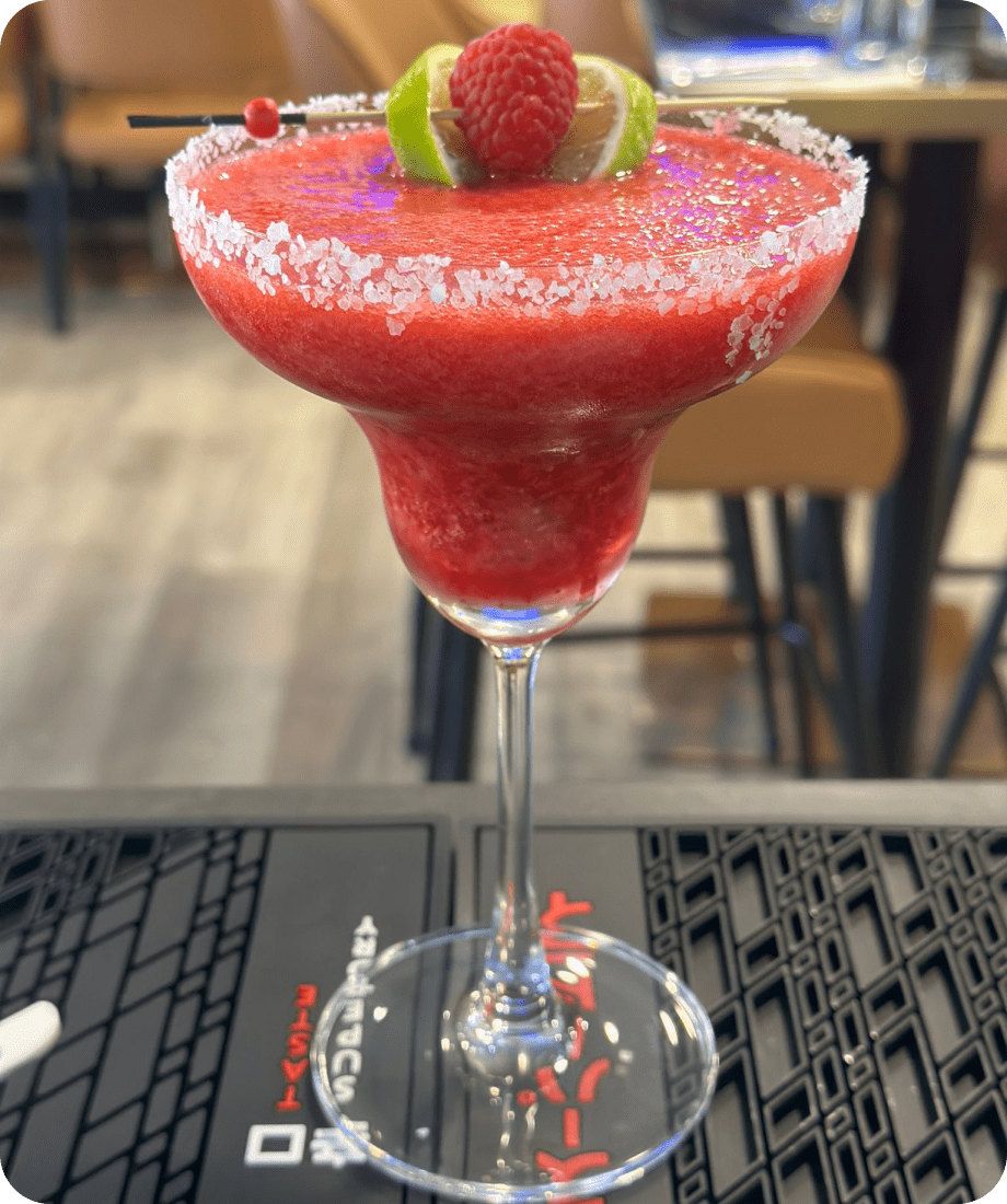 A refreshing virgin strawberry margarita served in a tall glass with a sugar-rimmed edge, garnished with a lime wedge.